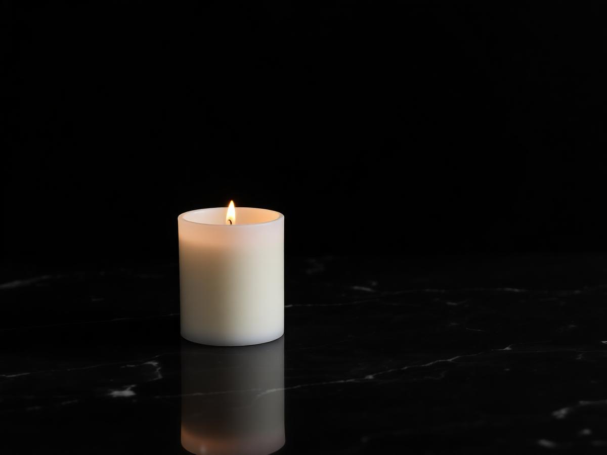 A memorial candle burning on dark marble